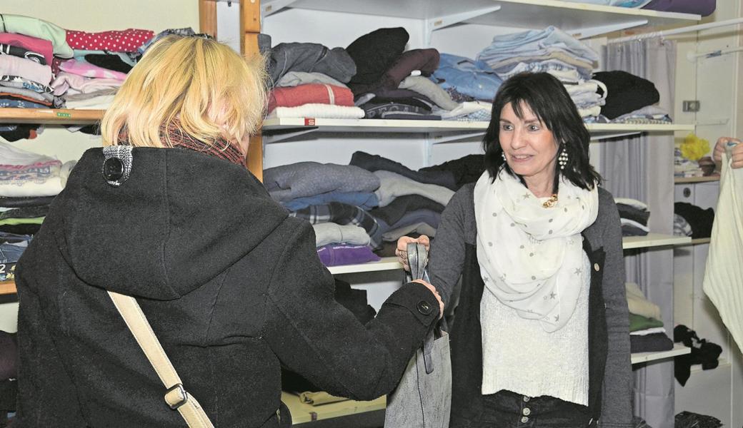 Silvia Meile zeigt einem ihrer Gäste eine Handtasche, die als Spende eingegangen ist.