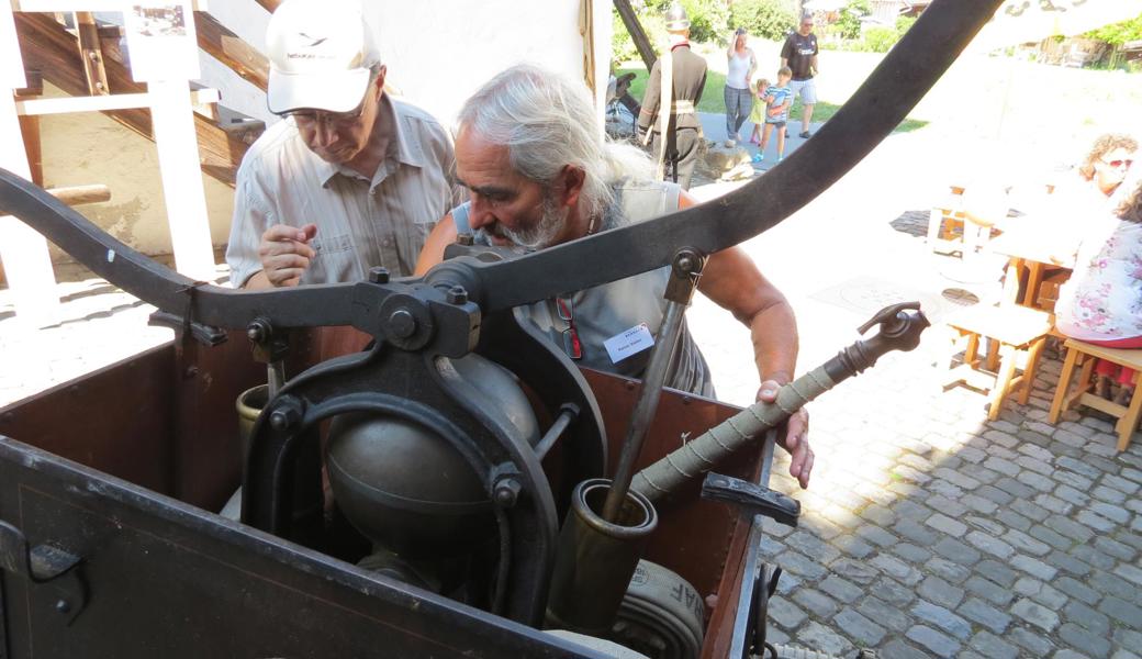 Rainer Sieber (r.) erklärt das Funktionieren der historischen Feuerspritze.
