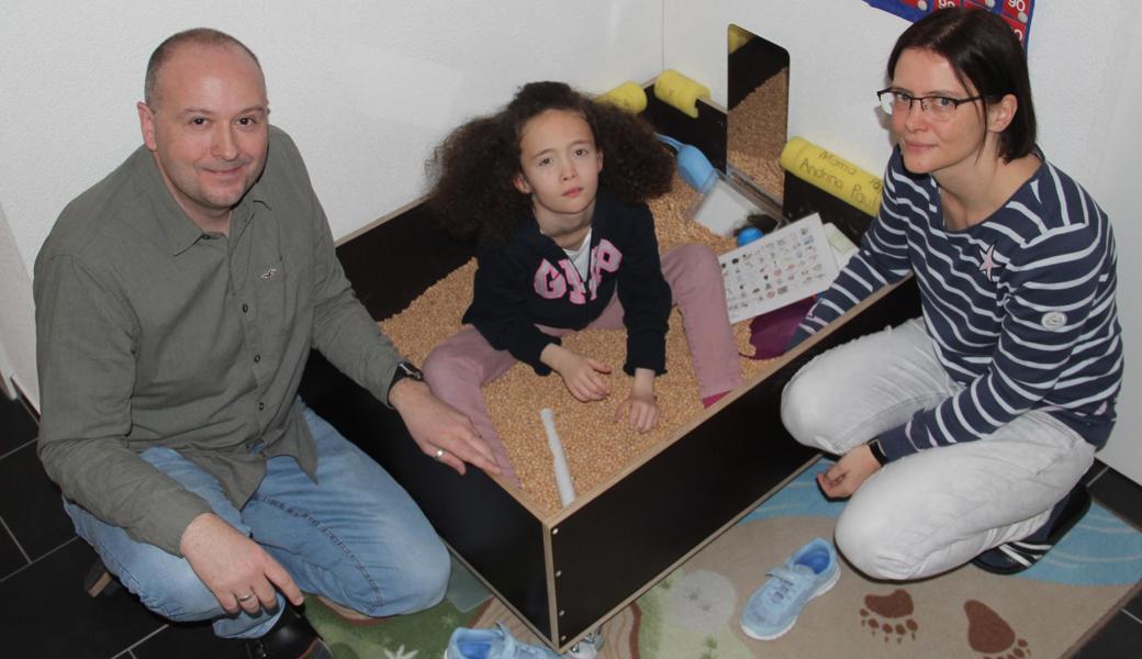 Andrina sitzt gern in der Chriesischtei-Chischte und lässt es rieseln. Der Sandkastenersatz diene der Körperwahrnehmung, erklären Benno und Katharina Dellai-Schöbi. Während dem Kind die Motivation, sich für irgendetwas zu interessieren, oft fehlt, dürfen die Eltern nicht nachlassen.