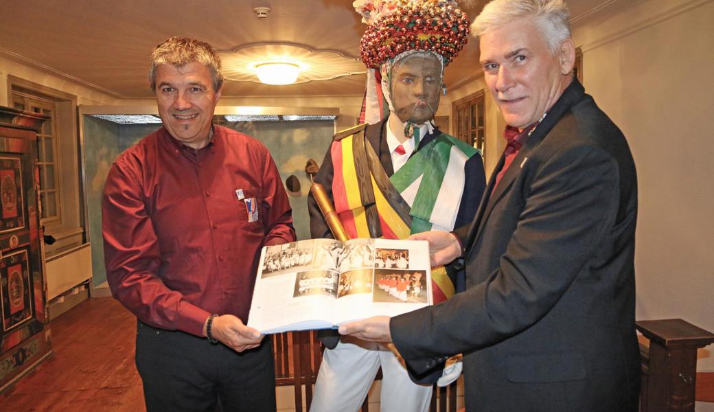 Bildband, Chronik, Festschrift: Mit dem Buch über die Altstätter Fasnacht halten Alex Zenhäusern, OK Präsident 100-Jahr-Jubiläum, (links), und Carlo Pinardi, Präsident Röllelibutzen-Verein, ein Zeugnis des Wandels in den Händen.