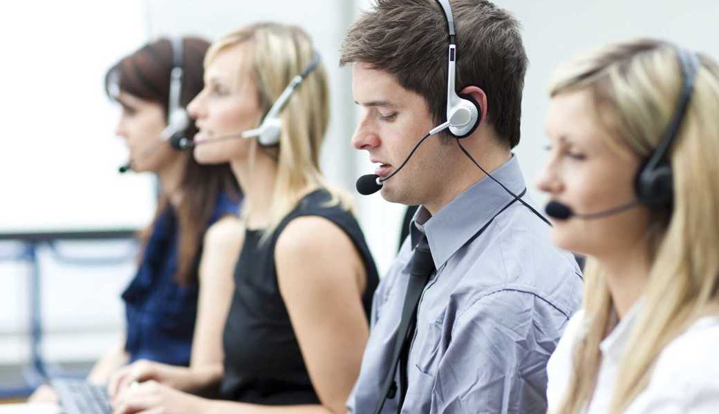 Attractive young man working in a call center with his colleagues