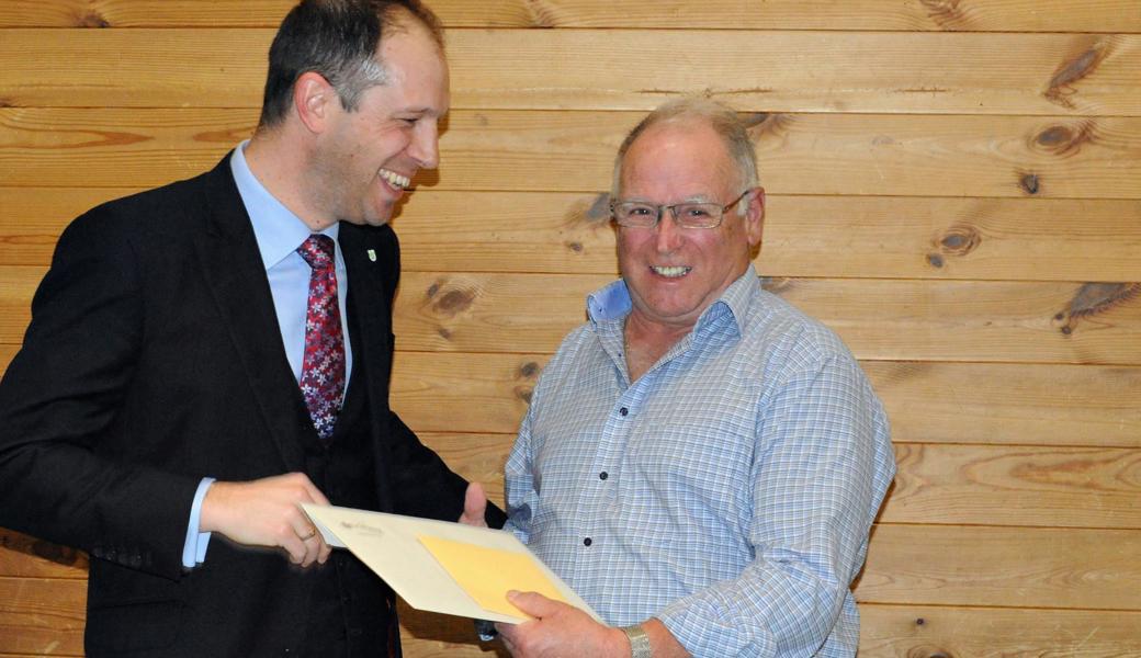 Gemeindepräsident Alex Arnold überreicht Peter Calonder (rechts) die Anerkennungsurkunde.