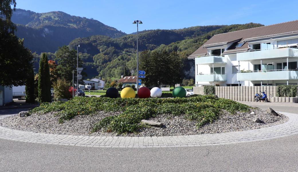 Die farbigen Kugeln im Oberrieter Kreisel  weichen einer Wildblumenwiese mit einer Linde. 