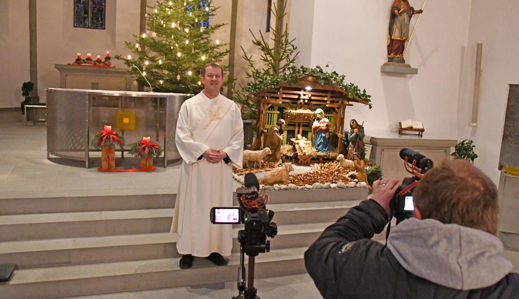 Raffael Gründeler zeichnet auf, wie Diakon Donat Haltiner vor der Krippe in der Montlinger Kirche zu den Menschen vor den Bildschirmen spricht: «Geht und bringt den Frieden vom Kind in der Krippe in die Familien und in die weite Welt.»
