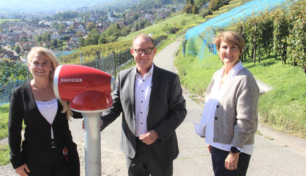 Der Bankleitungsvorsitzende Thomas Haas und Antonia Schegg (links) als Marketingleiterin von Raiffeisen Mittelrheintal freuen sich zusammen mit Balgachs Gemeindepräsidentin Silvia Troxler über das neue Erlebnisfernrohr beim Rebhüttli. 