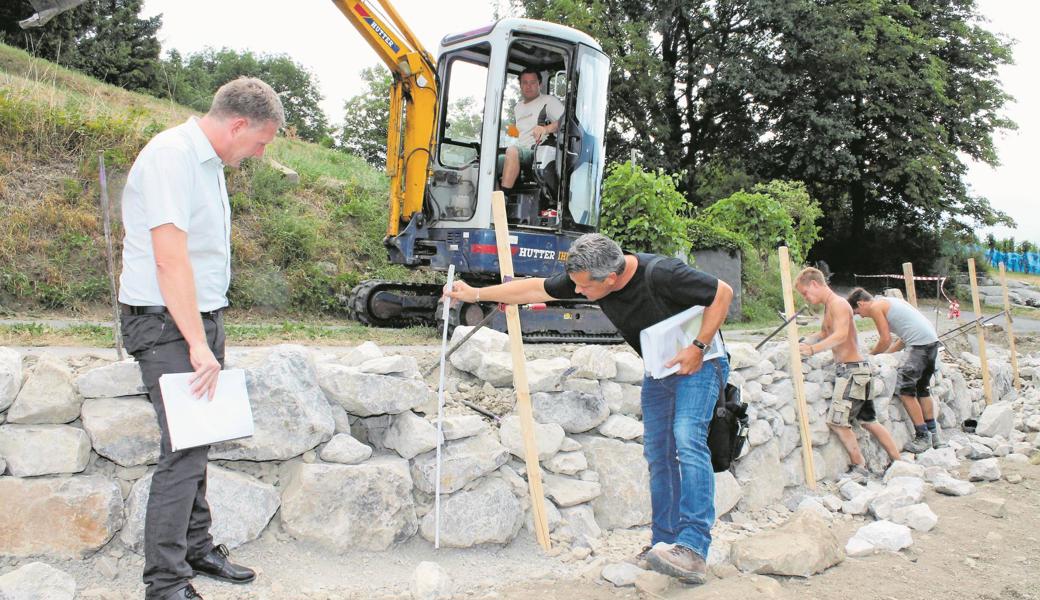 Gemeinderat Pascal Benz (l.) und der Widnauer Landschaftsarchitekt Nik Alge informierten über den Stand des Projekts. Rechts bauen die Gärtner an einer Trockenmauer.