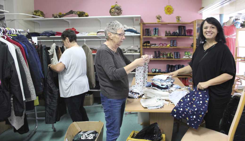 Die ehrenamtlichen Helferinnen Monika Brotzer und Susanne Stierli sowie Leiterin Maria Garcia Silva (von links) sortieren Kleider. 
