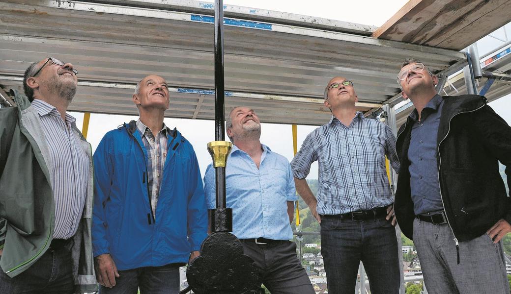 Gebhard Buschor (Pfleger, von links), Erwin Heeb (Präsident Liegenschaftskommission), Roger Benz (Präsident evangelische Kirchgemeinde), William Canal (Präsident katholische Kirchgemeinde) und Jürg Tobler (göldipartnerarchitekten) beobachten, wie der neu vergoldete Güggel montiert wird. Damit er sich im Wind dreht, ist er auf den historisch originalen Glaskugeln gelagert. 