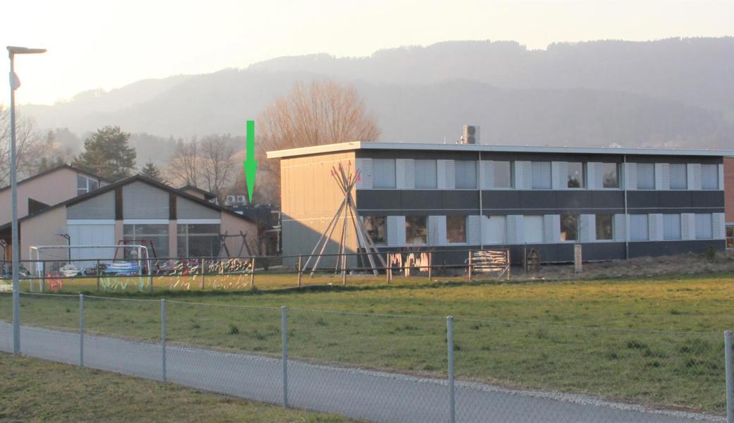 Vor fünf Jahren baute die Heilpädagogische Schule ihr erstes Provisorium – grosse schwarze Doppelstockcontainer (Bildmitte), in denen die vier Oberstufenklassen unterrichtet werden. Ein weiterer Doppelstockcontainer steht neuerdings auf der anderen Seite des Schulareals (grüner Pfeil). Aufs neue Schuljahr hin dürften nochmals zwei Container aufgestellt werden – wo, ist noch nicht beschlossen. Links ist das HPS-Gebäude zu sehen, rechts das Schulhaus der Oberstufe Mittelrheintal (OMR).