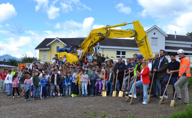 Ein Loch im Boden und ein Bagger auf der Wiese kündigen das entstehende neue Schulhaus an