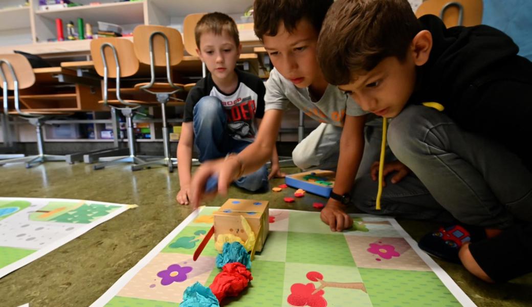 Dejan, Simon und Joussef haben ihren Holzwürfelroboter so programmiert, dass er die Papierknäuel vom Plakat räumt.