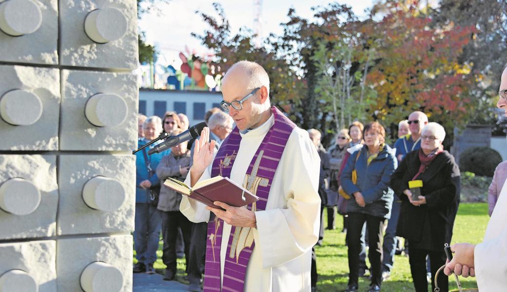 Der katholische Pfarrer Patrik Brunschwiler segnet den links sichtbaren neuen Kubus auf dem interkonfessionellen Friedhof in Widnau. Hinten rechts steht Mares Bächler, die den  ersten Zylinder der Urnengrabstätte ins Freiburgerland mitnehmen wird.