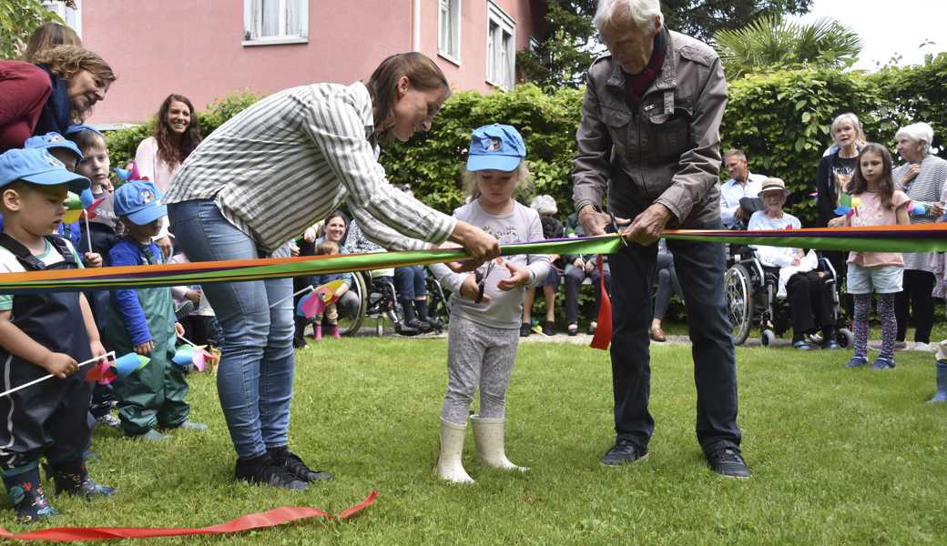 Der neue Spielplatz ist eröffnet: Emma von der Kita Rägeboge und Altersheimbewohner Rolf Büsser zerschneiden das Band.