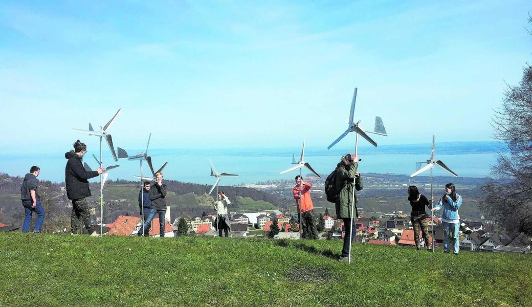 Schülerinnen und Schüler testen die Windräder auf einer Wiese oberhalb des Dorfes. 