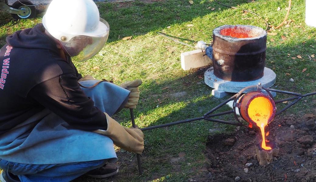 Gut geschützt giesst der Diepoldsauer Tom Hämmerle im Garten seiner Eltern glühendes Metall in die vorbereitete Glockenform.