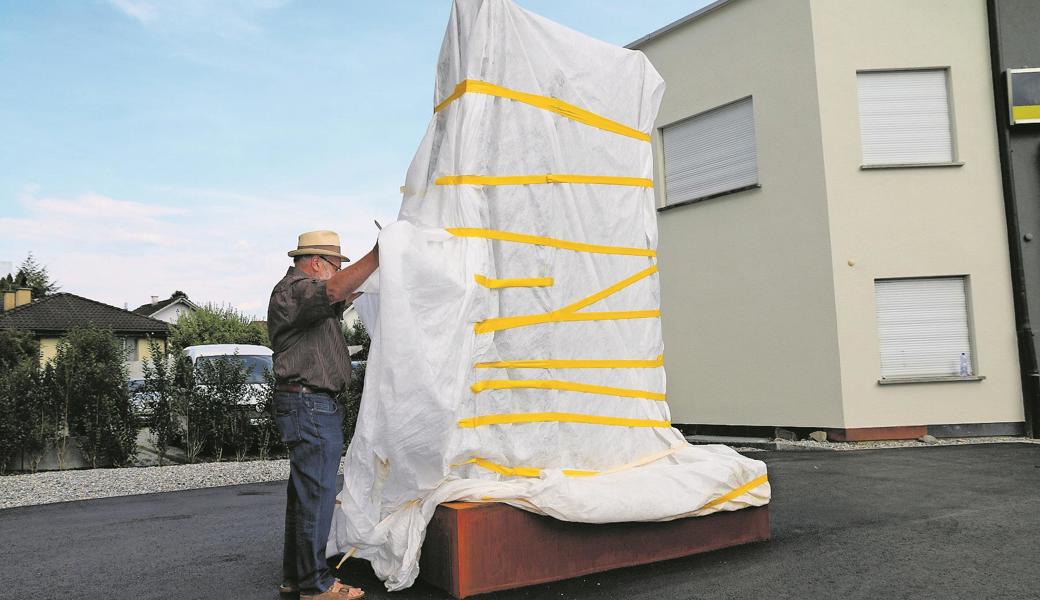 Mit mehreren Handgriffen und der Hilfe einer Baulatte enthüllte Peter Federer sein Kunstwerk «Begegnung» vor dem Neubau beim Nüesch-Kreisel.