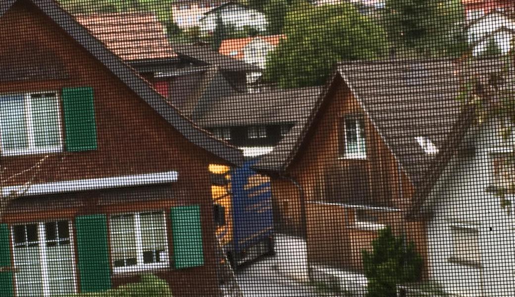 Sattelschlepper mit Anhänger auf der engen Kreuzung Rietstrasse/Im Roosen (fotografiert durch ein Fenster mit Insektengitter).