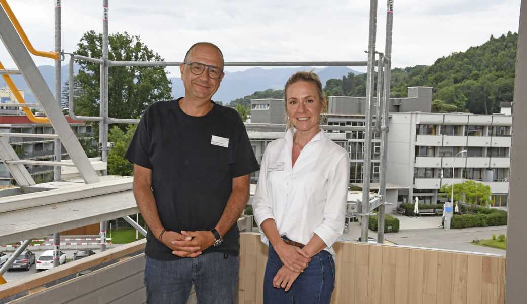 Martina Künzler (Leiterin Alters- und Pflegeheim Fahr) und Alexander Raggl (Leitung Pflege und Betreuung) begutachten den Baufortschritt im Anbau Rosengarten. Im Hintergrund ist das Haupthaus Fahr zu sehen.