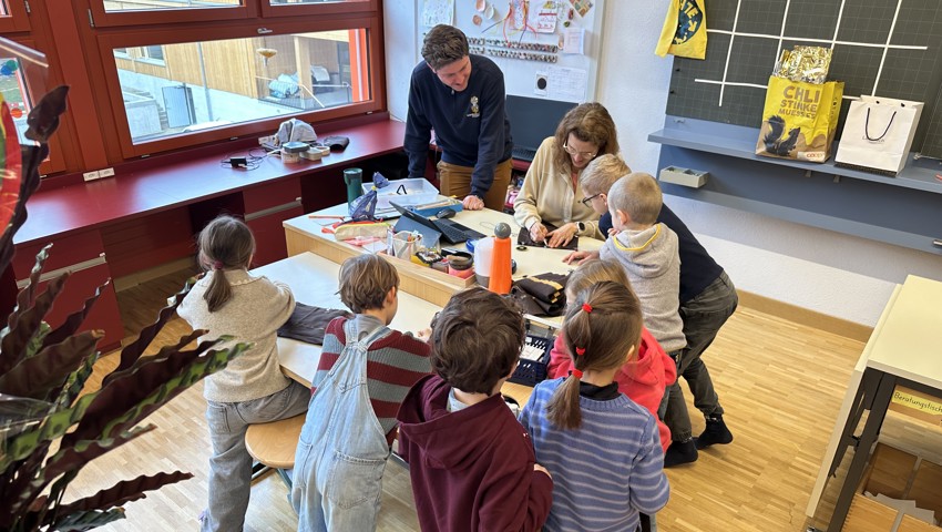 Der Altstätter Fasnachts-OK-Präsident Leonardo Pinardi schaut der Lehrerin Bettina Breu sowie den Schülerinnen und Schülern bei den Bastelarbeiten ihres Kostüms über die Schultern.