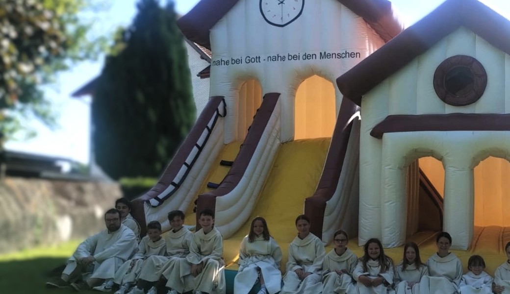 Ministrantinnen und Ministranten warten im Schatten auf ihren Einsatz.
